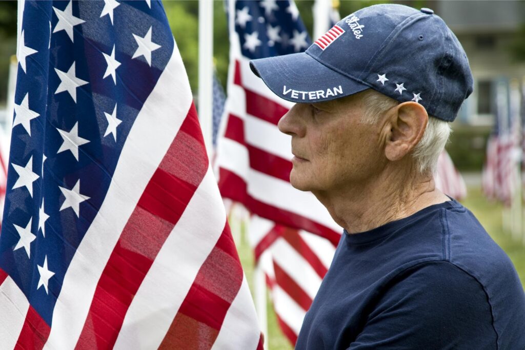 A veteran standing proudly in front of an American flag.