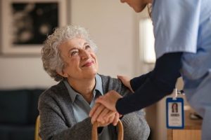 Caregiver reassures a seated senior holding a cane