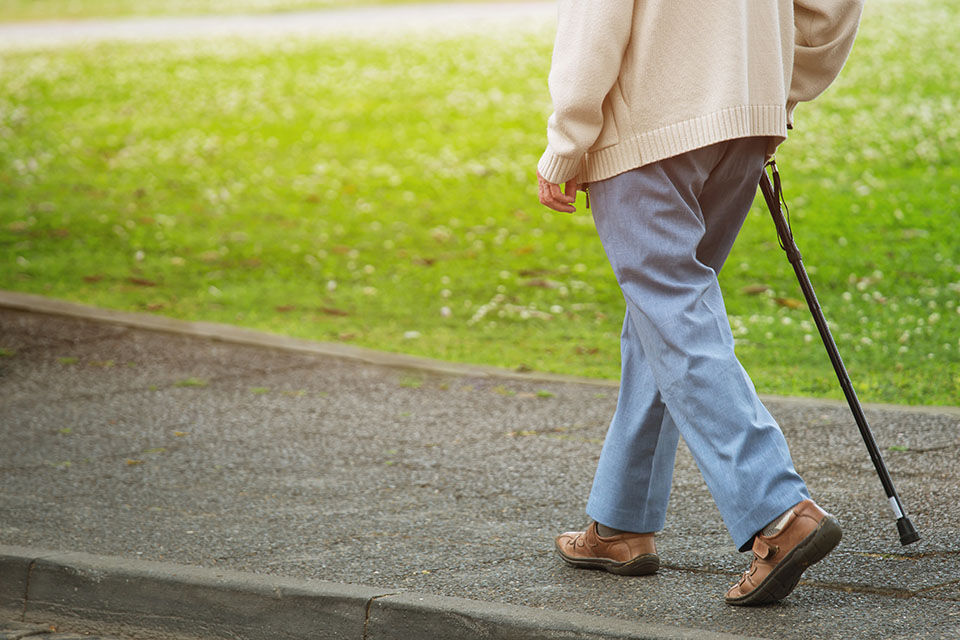 elderly man with walking stick stand on footpath sidewalk