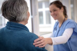 Smiling female nurse comforting senior patient 